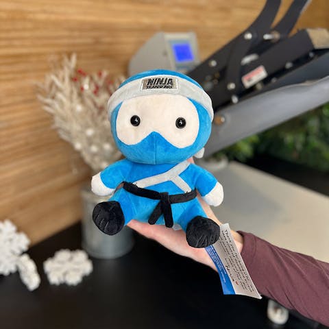 Ninja Transfers plushie being held in front of heat press