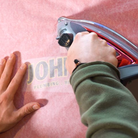 household iron being used to press a dtf transfer on a shirt